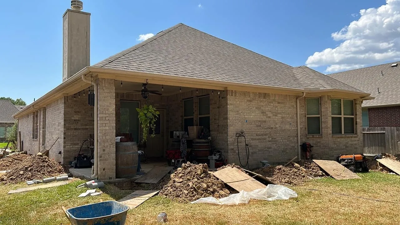 Excavated access points along the foundation of a brick residence during repair work